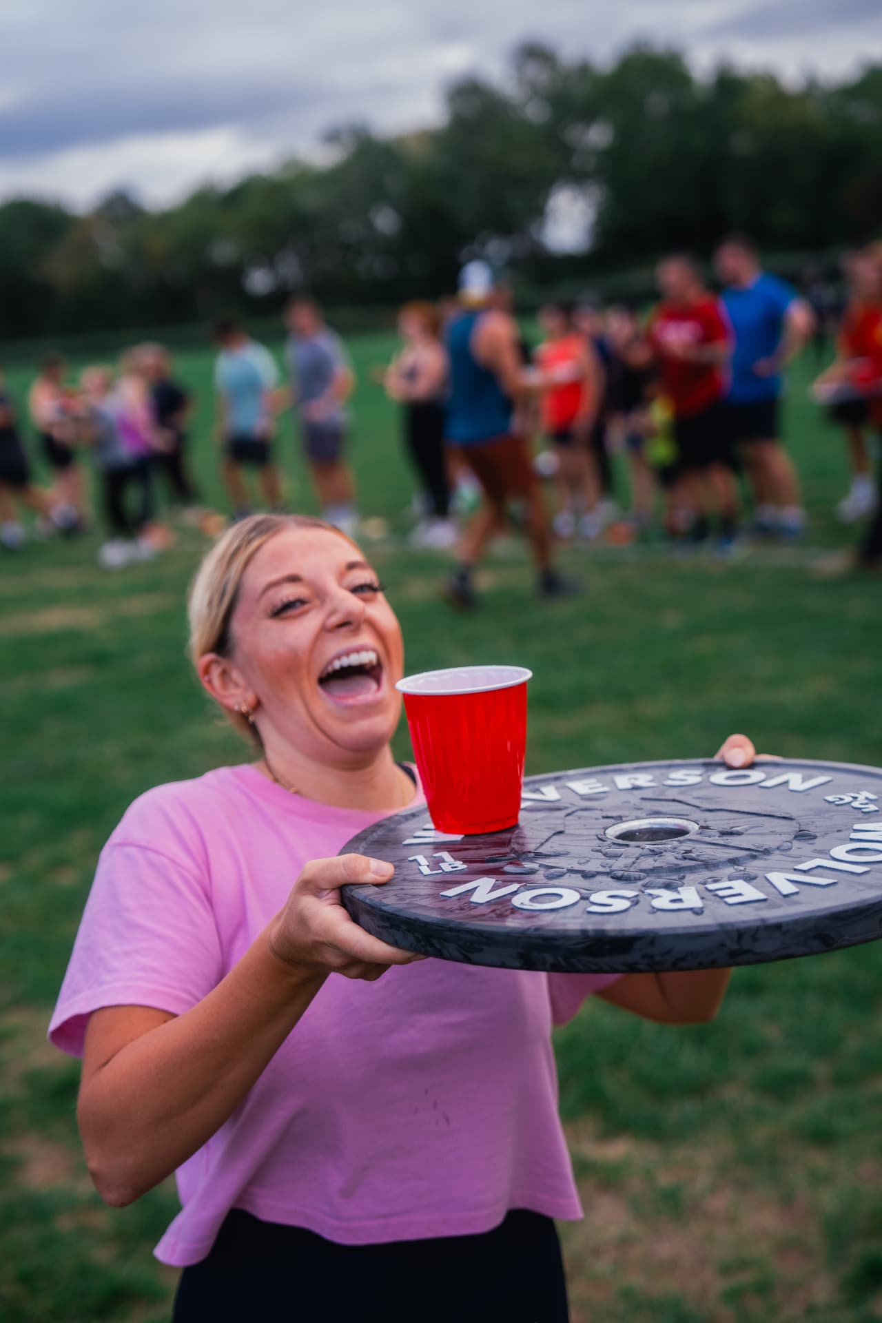 A member laughing while carrying a weight plate in the anniversary relay